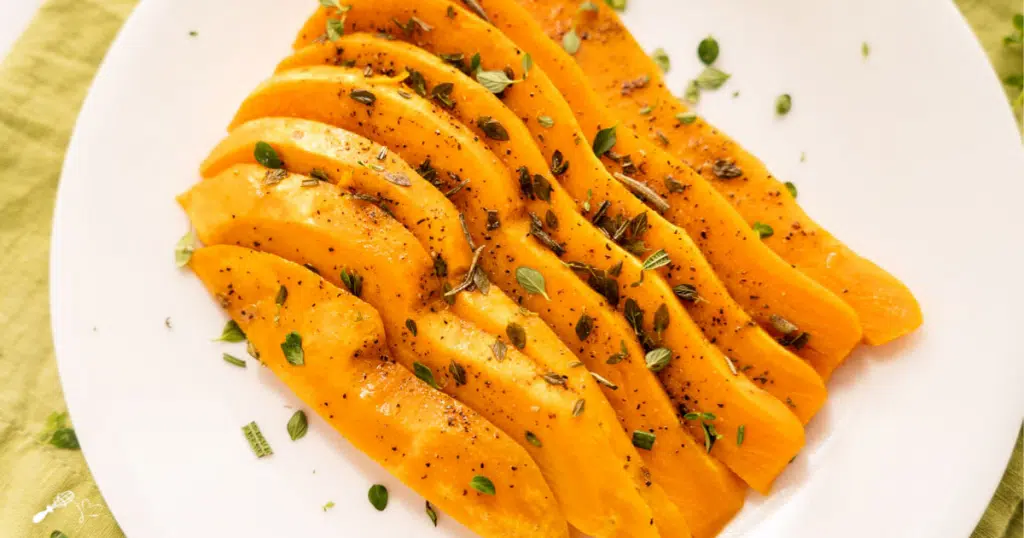 Top down photo of sliced sweet potatoes garnished with fresh herbs.