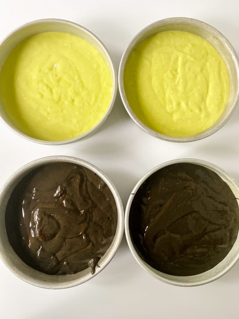 two pans filled with chocolate cake batter and two pans filled with green cake batter.