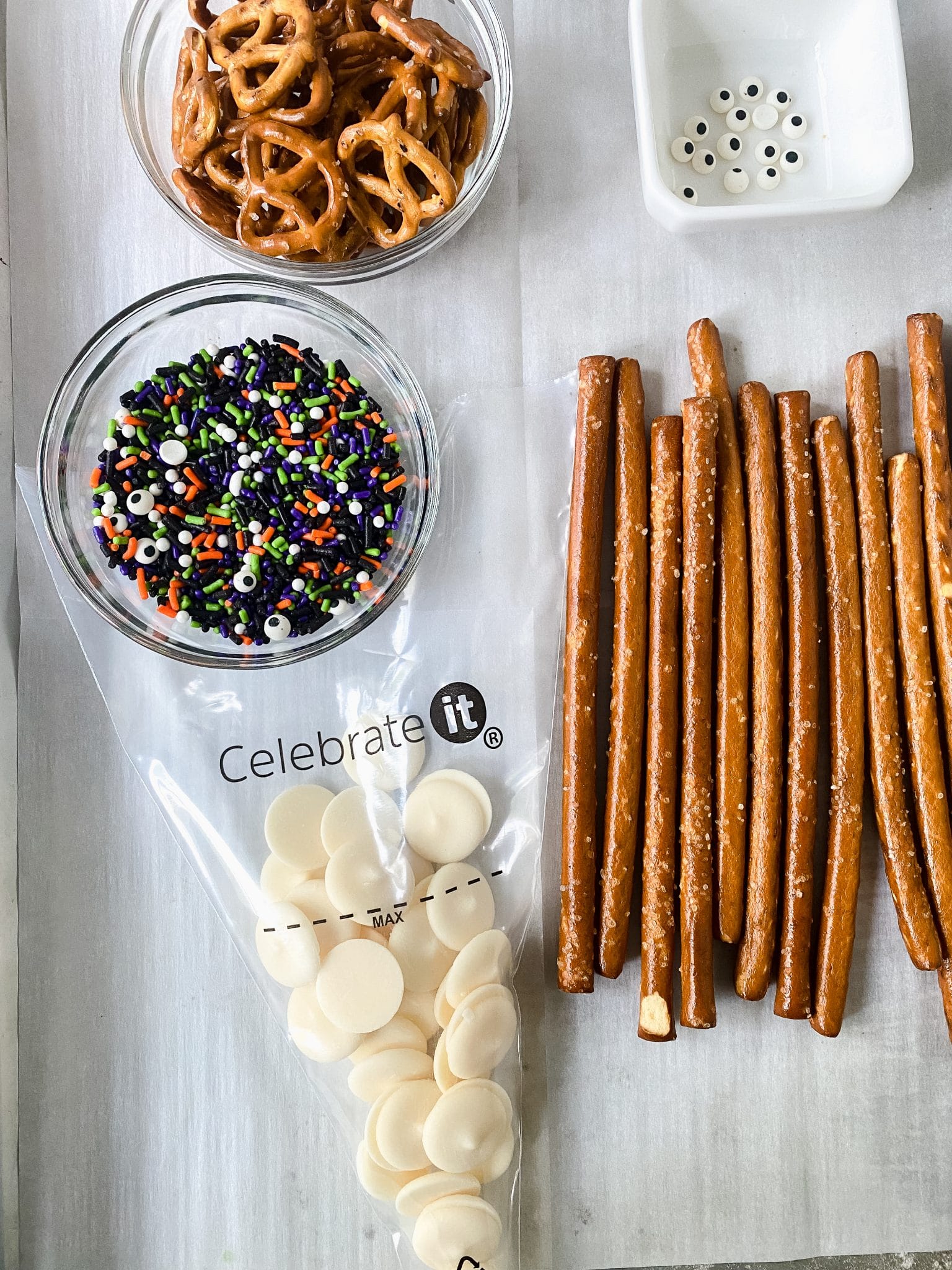 Ingredients for chocolate covered pretzels, including candy melts, sprinkles, and pretzels.