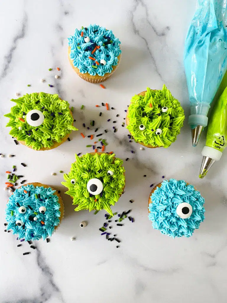 Monster cupcakes close-up with green and blue frosting and candy eyes.