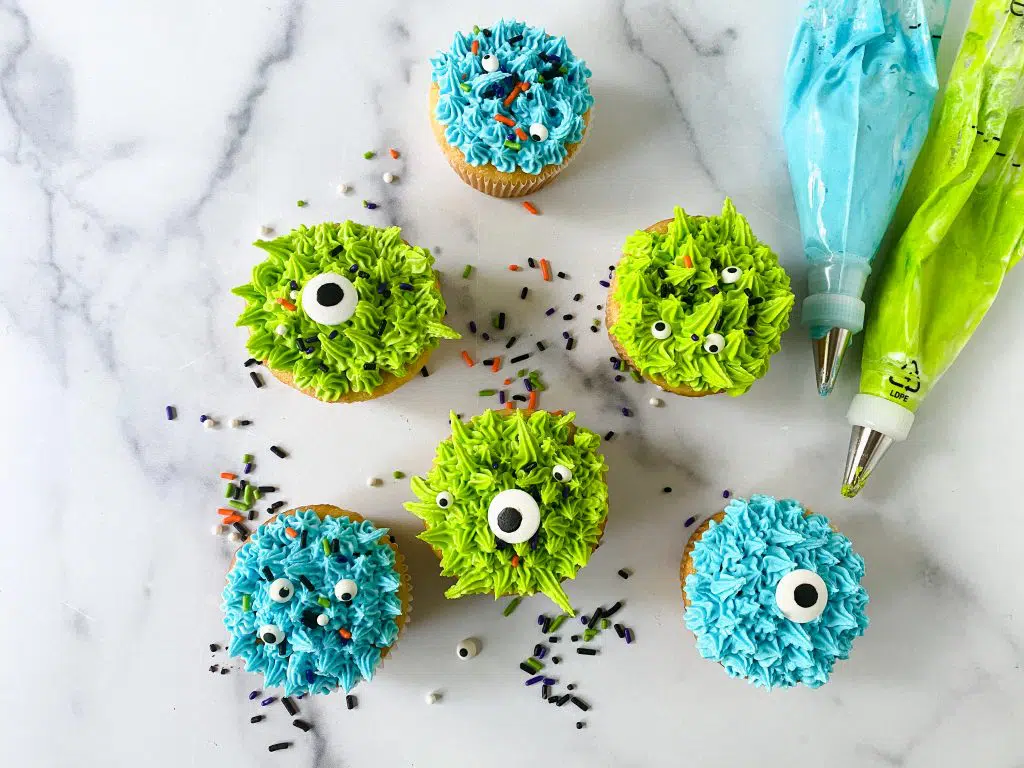 monster decorated cupcakes shown with piping bags filled with frosting.