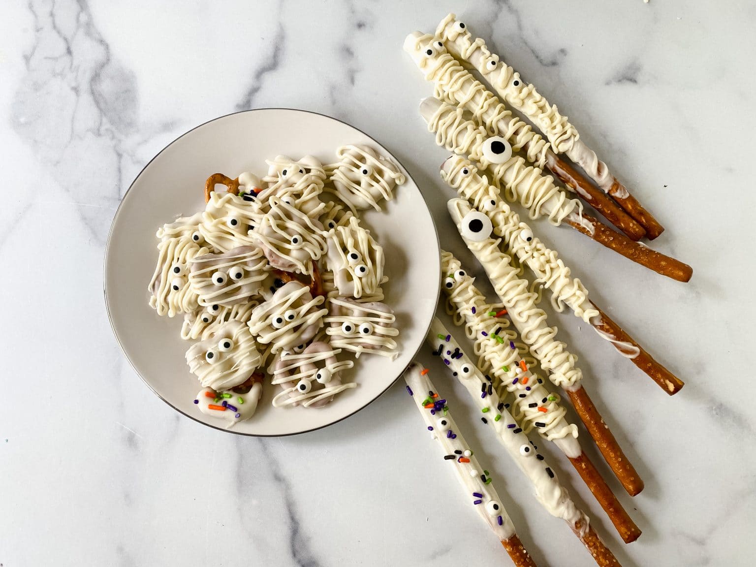 Mummy Pretzels and Halloween Pretzel Rods on a platter displayed on a counter.