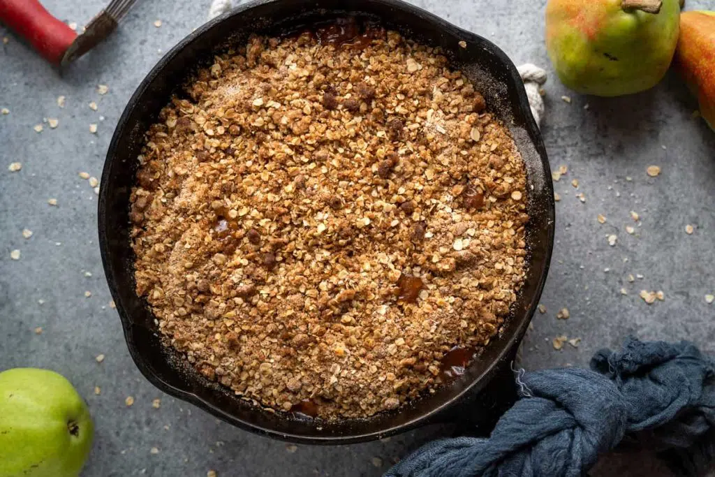 Top Down photo of a cast Iron skillet filled with baked pear crisp topped with streusel with oats.
