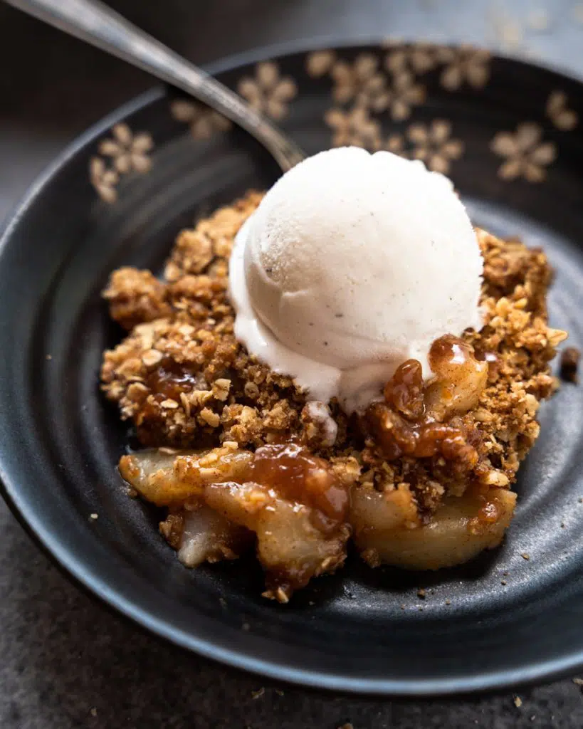 Individual serving of pear crisp shown in a dish with ice cream.