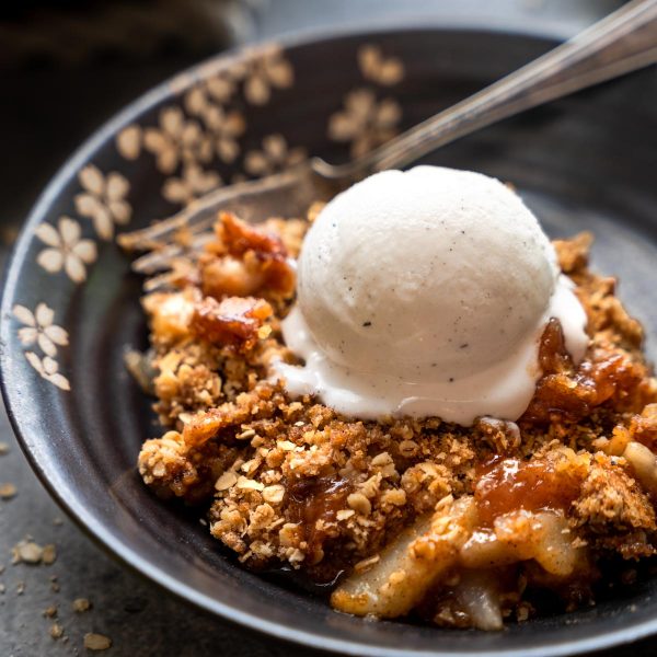 3/4 view of a serving of pear crisp topped with ice cream.
