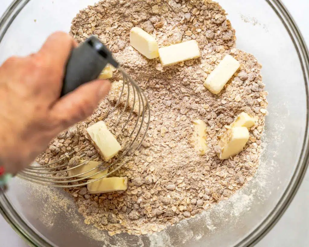 Mixing bowl containing streusel ingredients being combined with a pastry cutter.