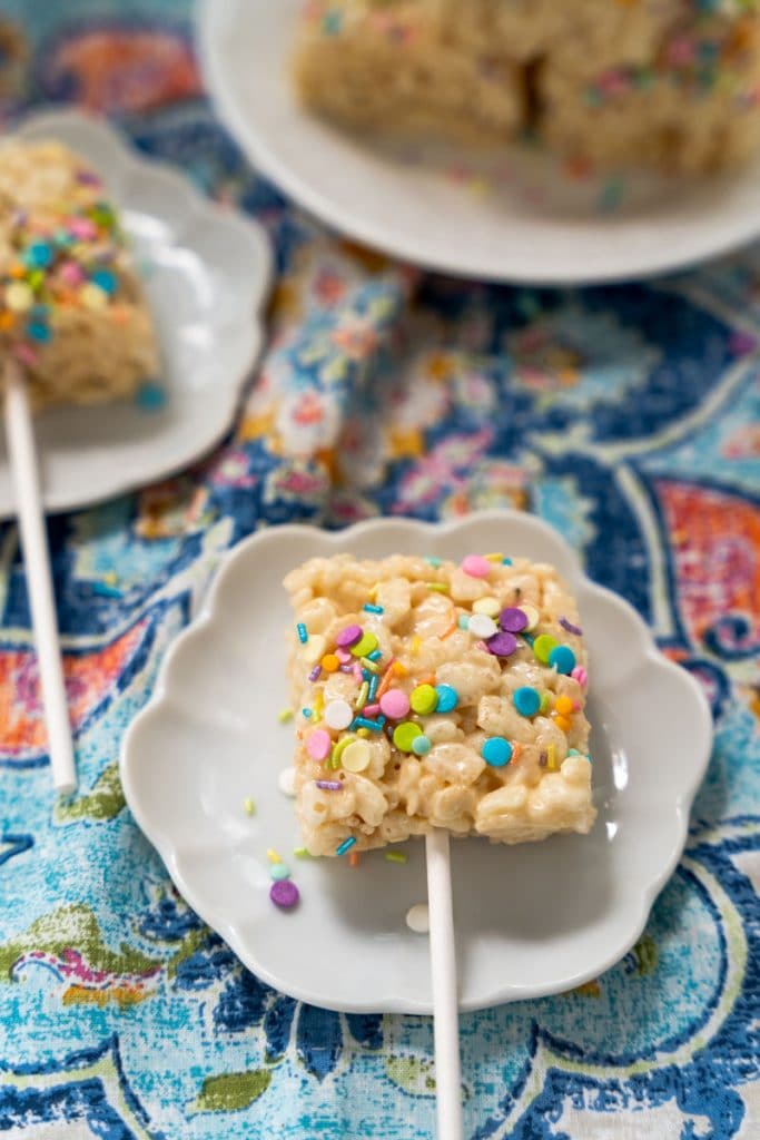 A Rice Krispy Treat lollipop garnished with colorful sprinkles.