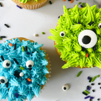Top down view of two cupcakes decorated to resemble monsters.