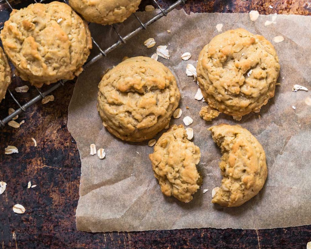 Three oatmeal cookies on a piece of parchment paper.