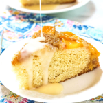 A slice of cake topped with peaches and an icing drizzle.