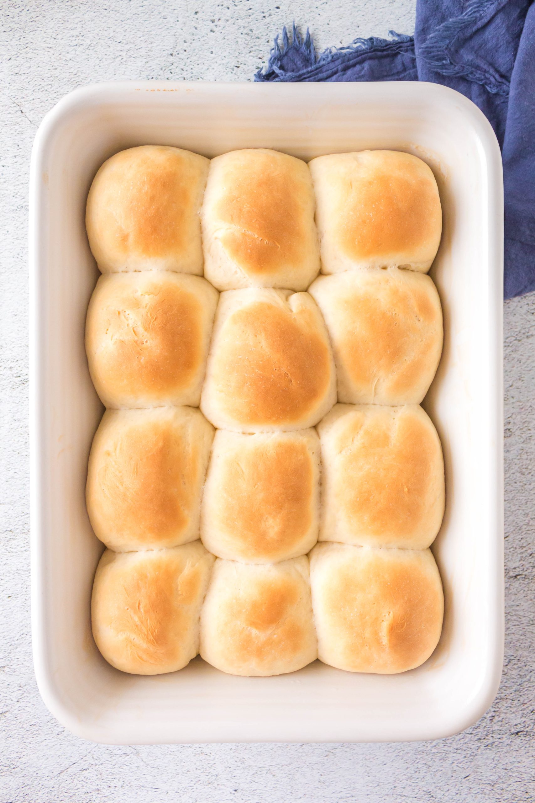 Top down view of golden brown dinner rolls in a baking dish.