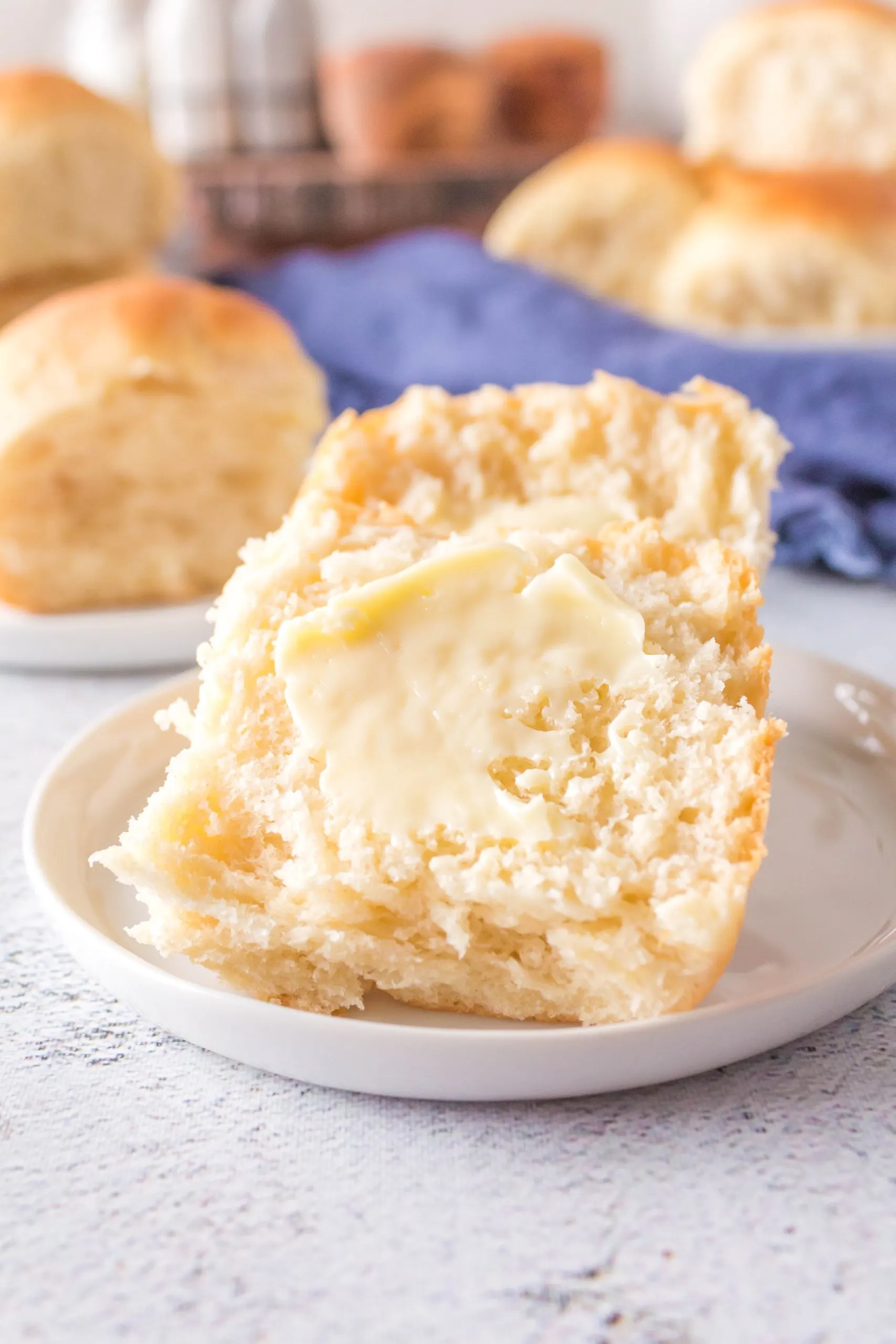 A soft and fluffy dinner roll slathered with butter - Hostess At Heart