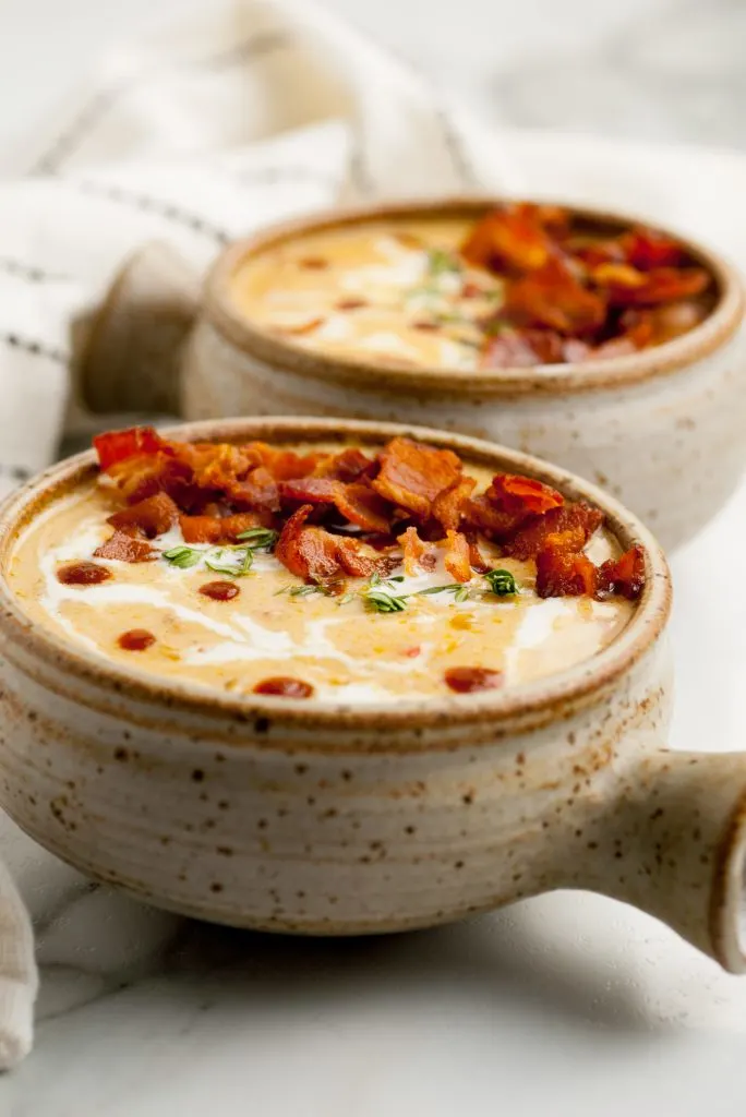 Beer Cheese soup in two bowls topped with crispy bacon.