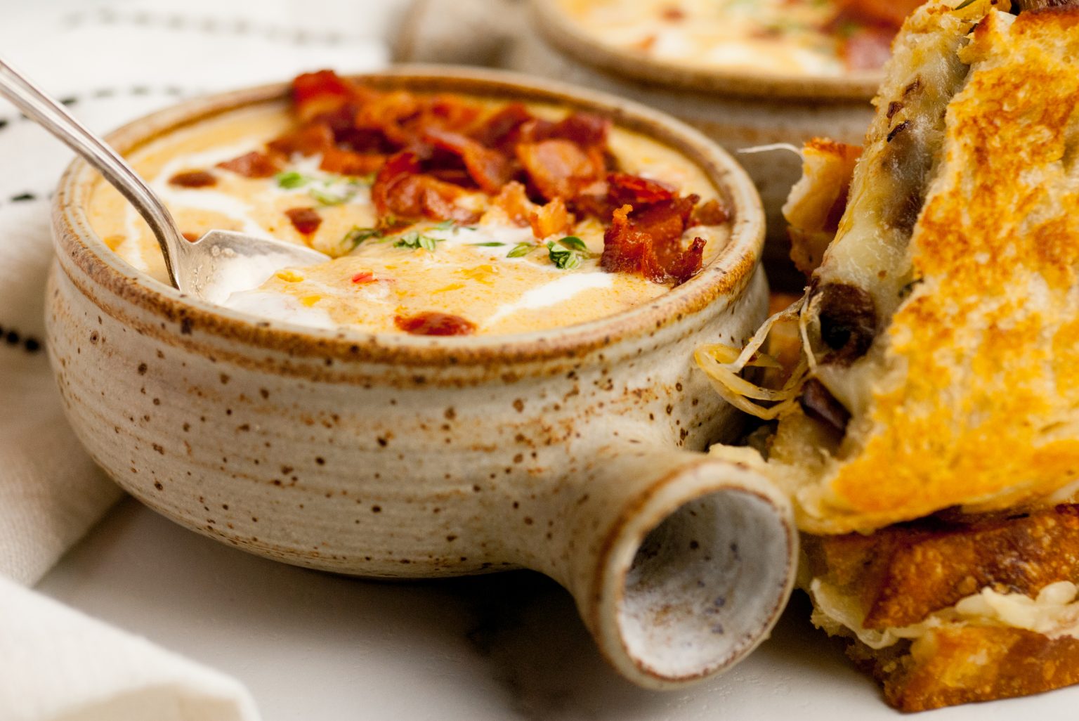 Beer cheese soup in a bowl shown with a sandwich.