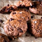 Close up of chocolate cookies dotted with chocolate chops and nuts.