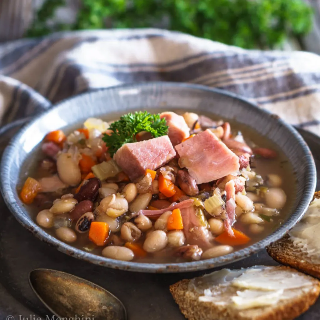 A bowl filled with ham, beans, carrots and celery.