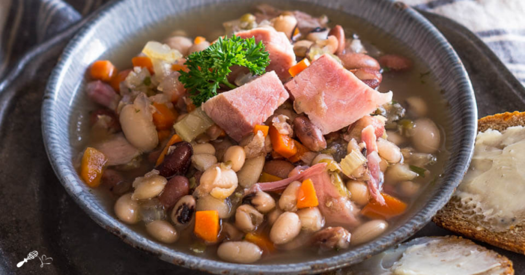 A bowl filled with ham, beans, carrots and celery.