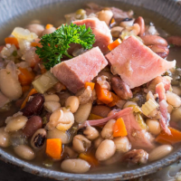 A bowl filled with ham, beans, carrots and celery.