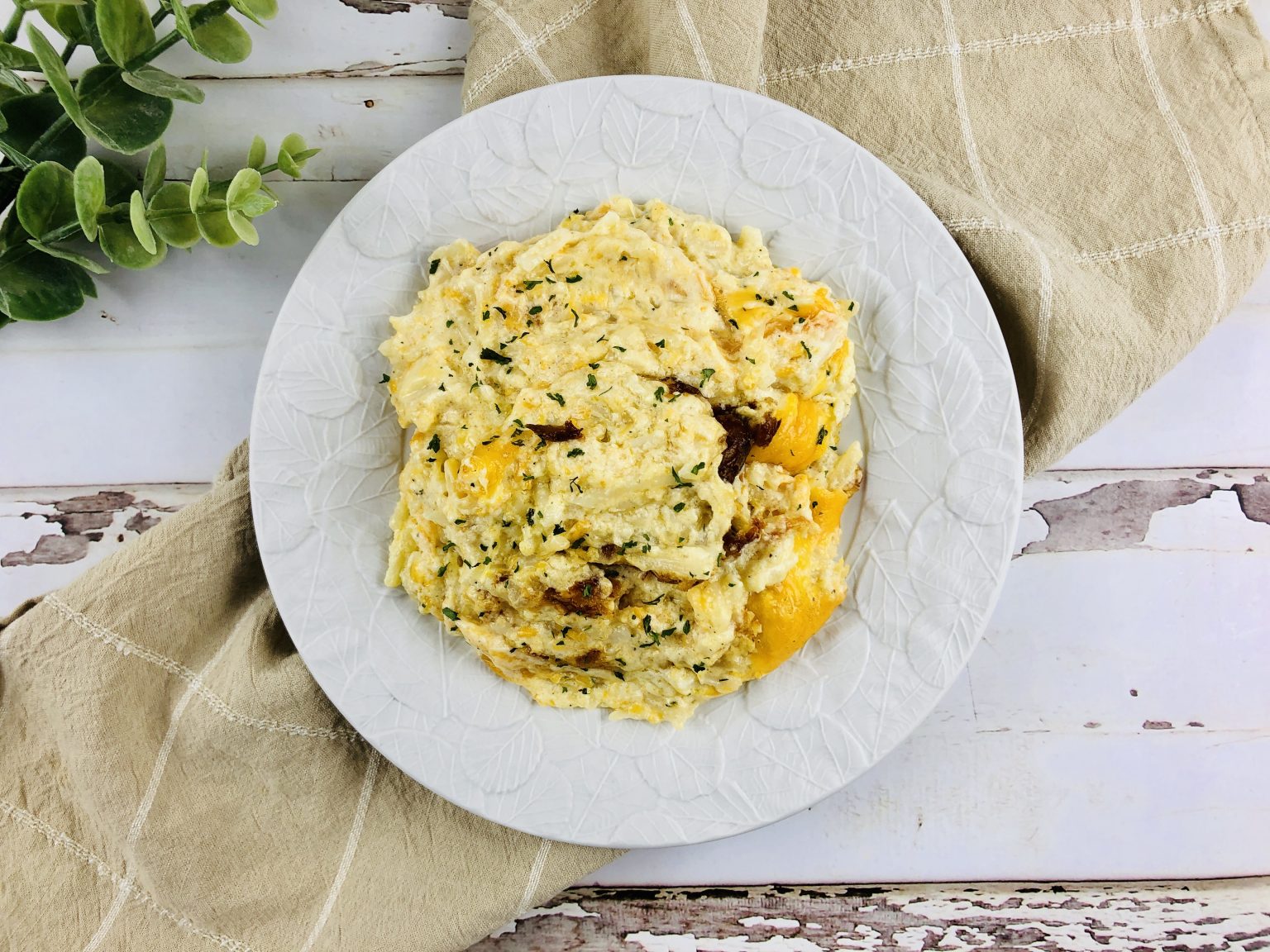 Top Down view of cheesy hashbrowns on a plate.