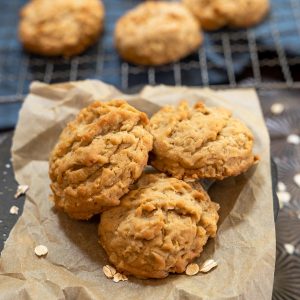 Top down view of three cookies sitting on a piece of parchment paper with a rack of cookies sitting in the background.