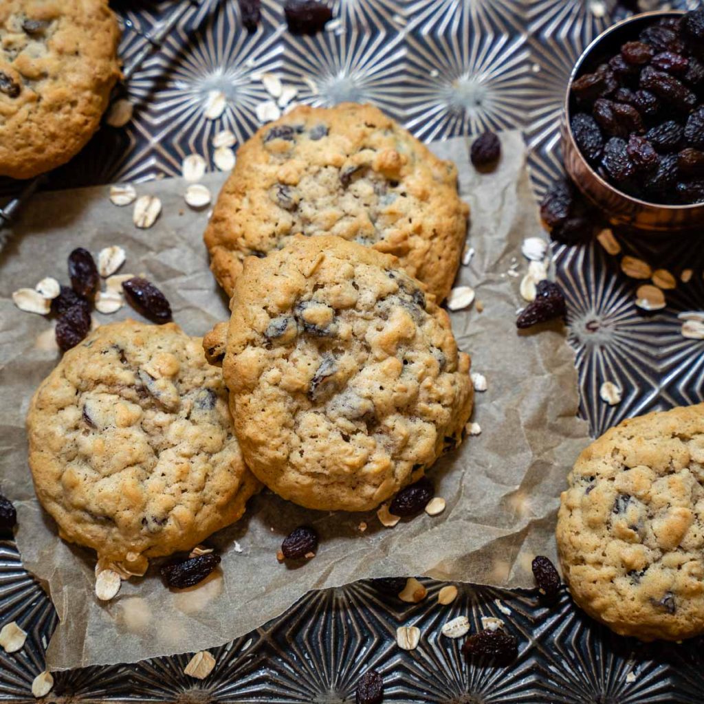 Top down view of soft and chewy Oatmeal Raisin Cookies sitting on parchment paper lining a baking sheet - Hostess At Heart