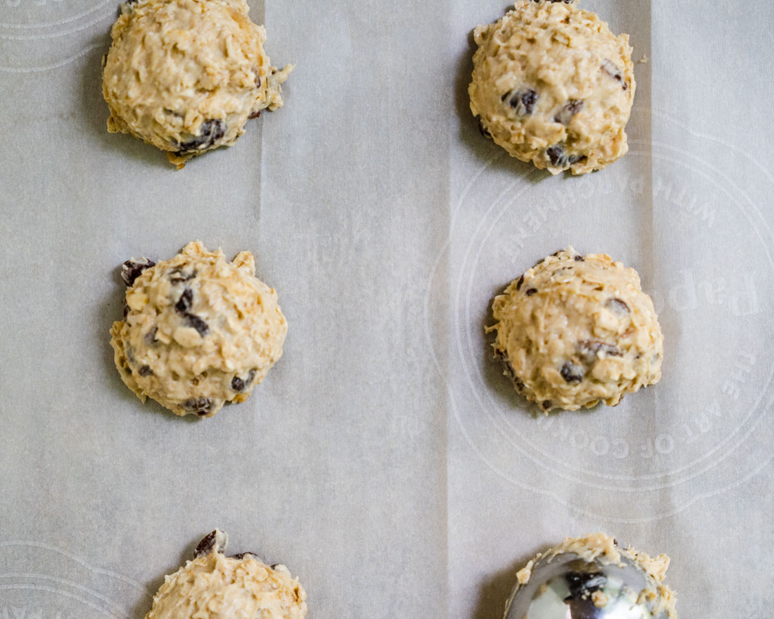 Homemade Oatmeal Raisin Cookie batter scooped onto a parchment paper lined cookie sheet. -Hostess At Heart