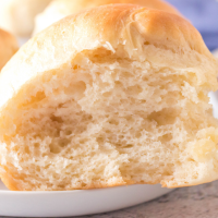 Close-up side-view of a dinner roll on a plate.