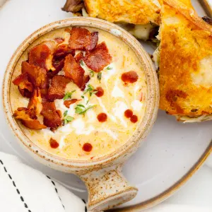 Top down view of cheese soup garnished with bacon and thyme.