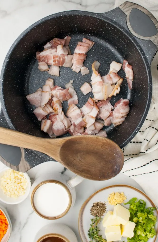 Pieces of bacon cooking in a skillet