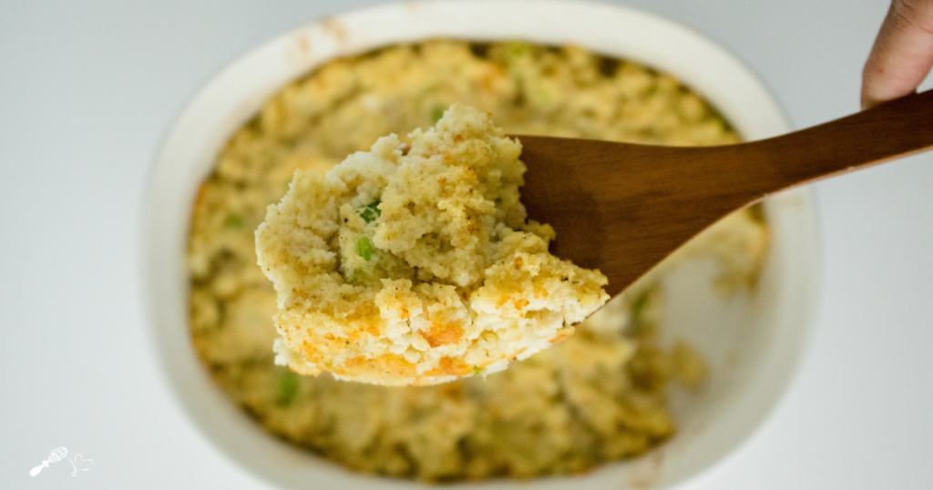 A spoonful of cornbread dressing hovering over the serving dish.