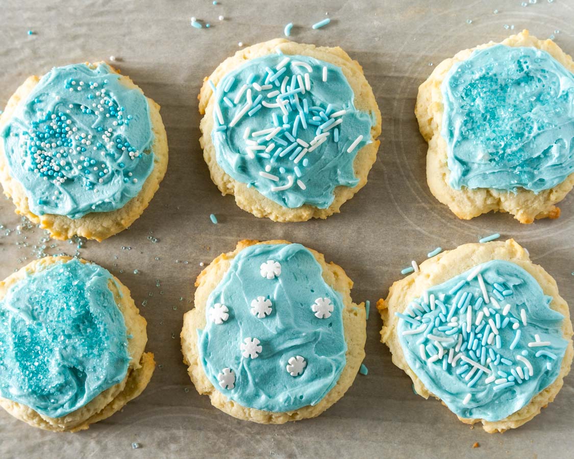 Top down view of 6 cookies with blue frosting and sprinkles