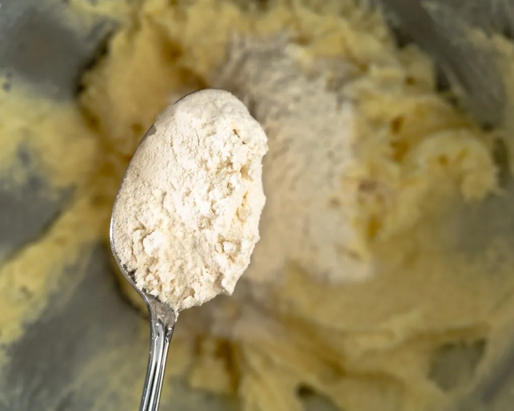 A tablespoon of flour being added to blended cookie dough