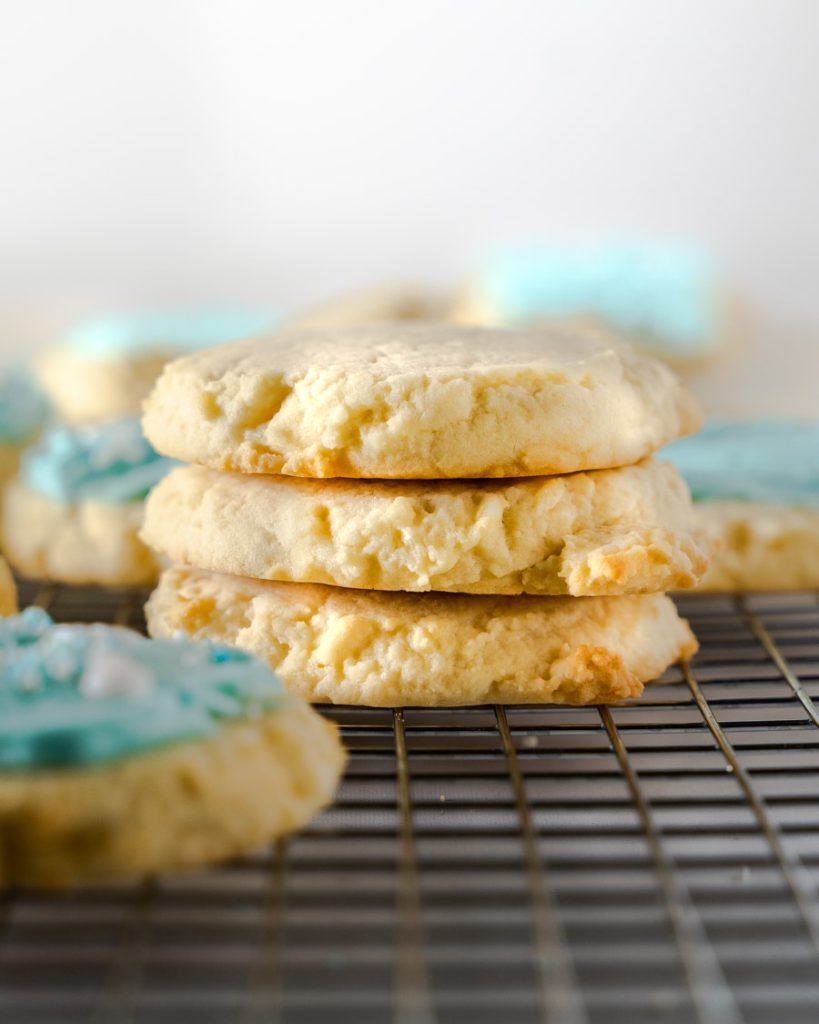 Sideview of stacked sugar cookies sitting on a cooling rack.
