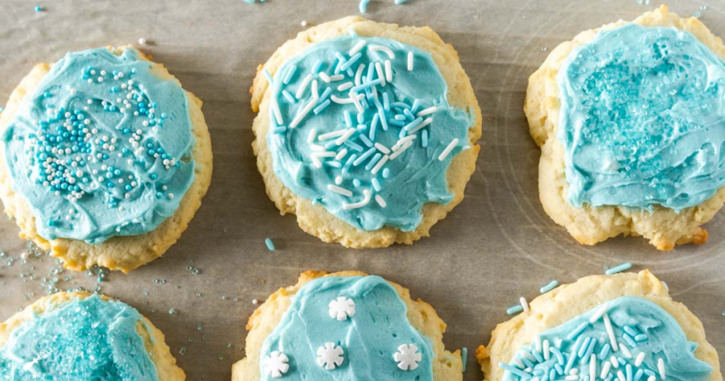 Top down view of 6 cookies with blue frosting and sprinkles.