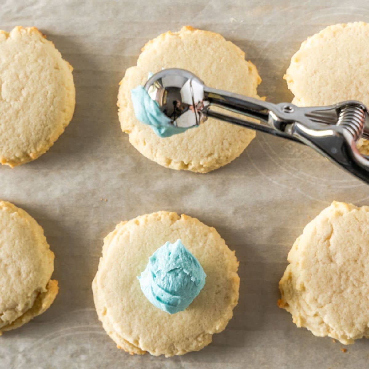 Homemade crumble sugar cookies with a dollop of blue frosting on top. Hostess At Heart