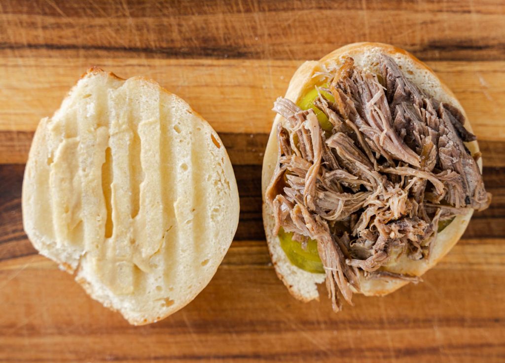 Shredded pork and pickles layered on a buttered roll