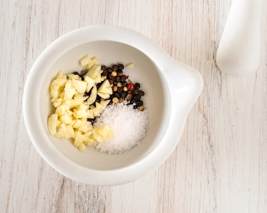 Garlic, peppercorns, and salt in a pestle.