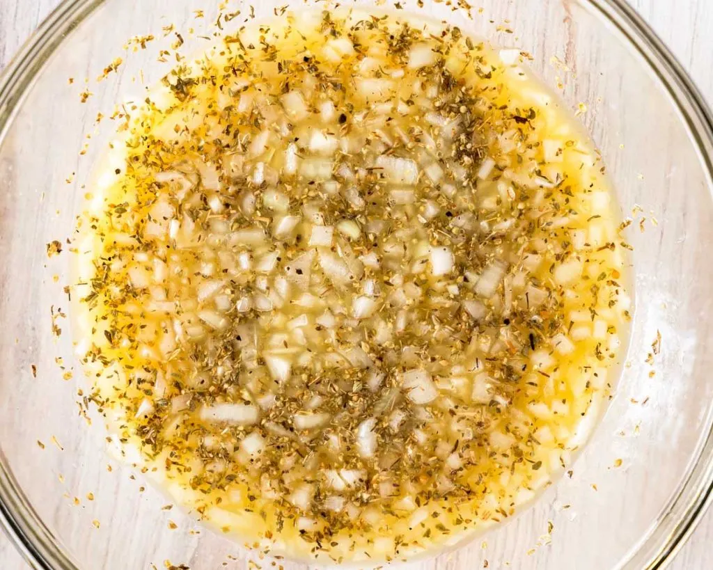 A bowl filled with mojo pork marinade of onions, seasonings, and orange juice.