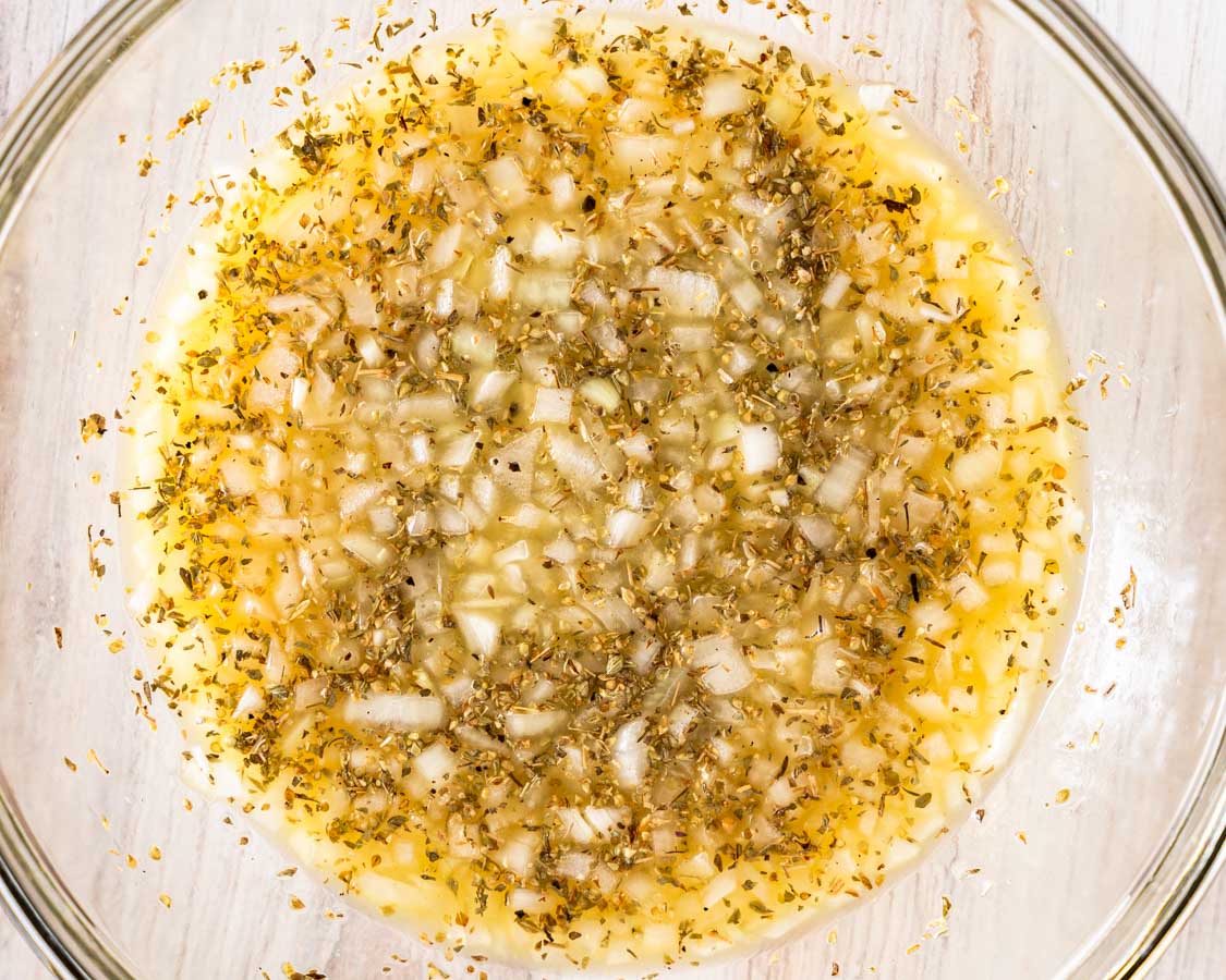 A bowl filled with mojo pork marinade of onions, seasonings, and orange juice.