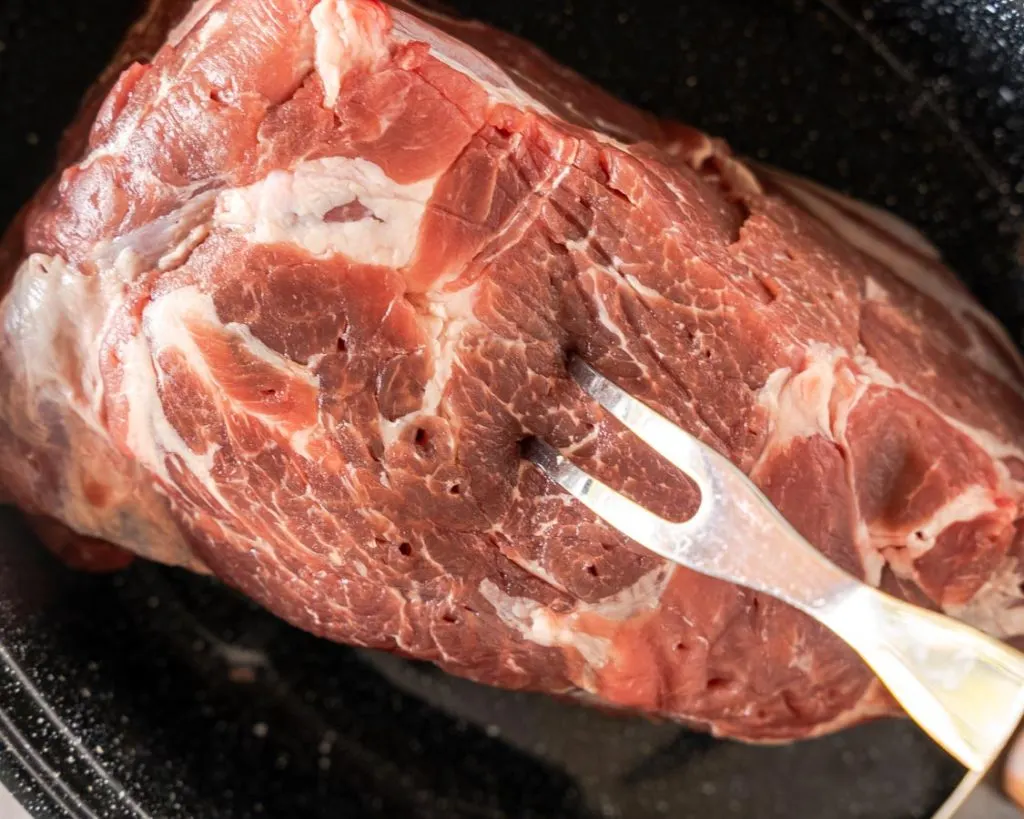 A fork piercing a pork butt.
