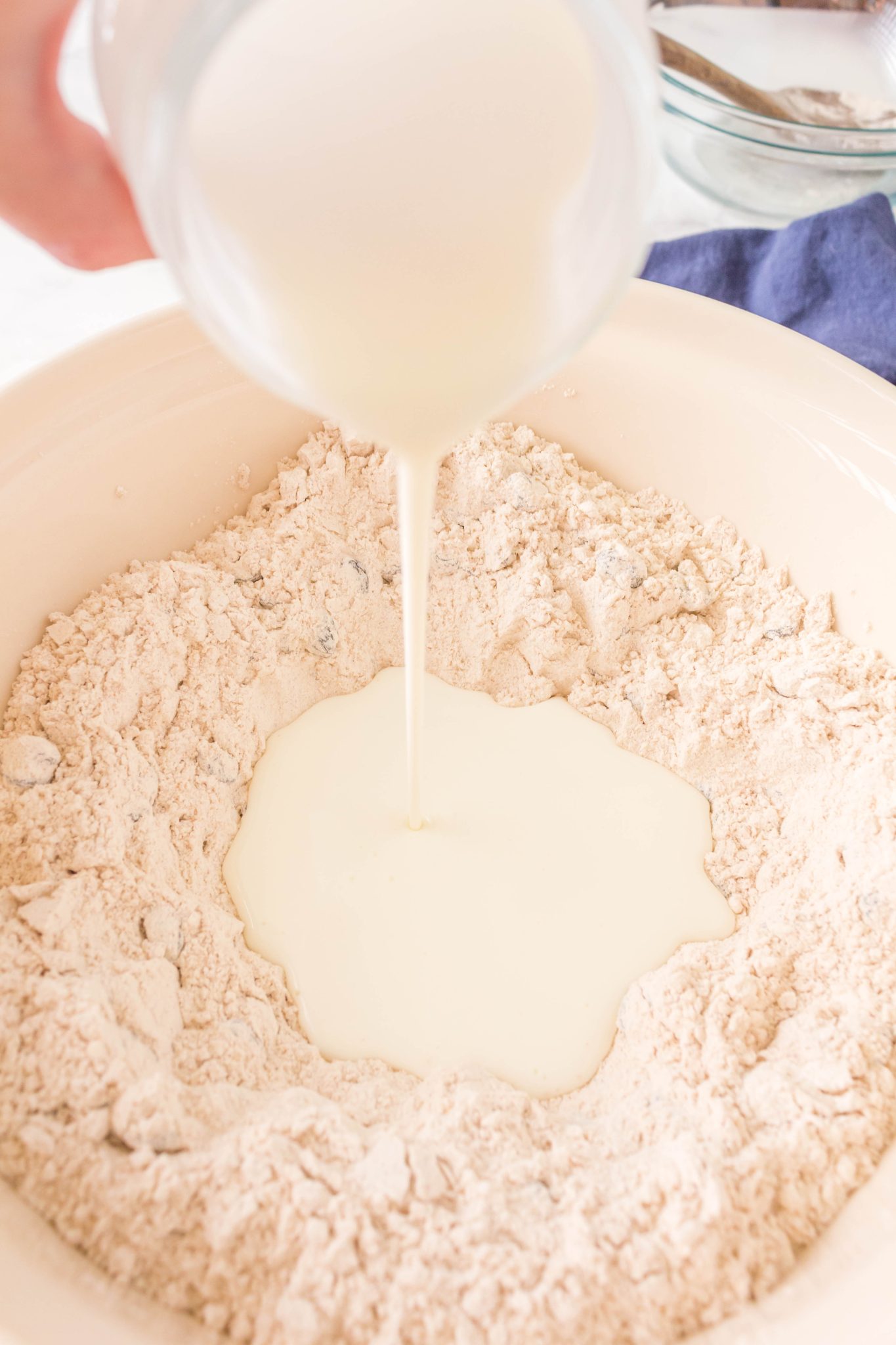Buttermilk being poured into a well of flour.