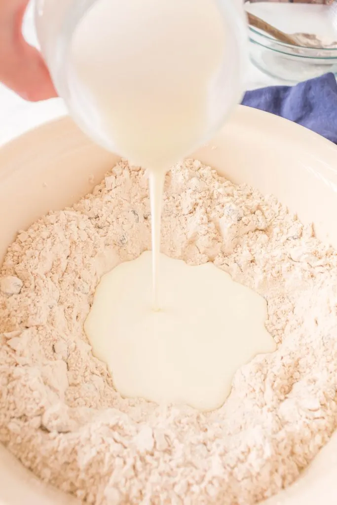 Buttermilk being poured into a well of flour.