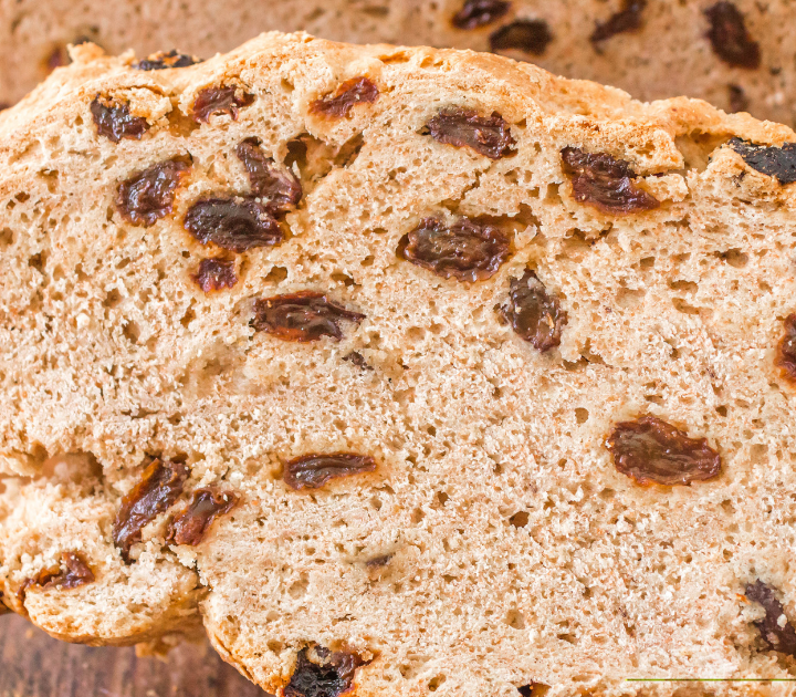 3/4 view of a slice of soda bread filled with raisins.