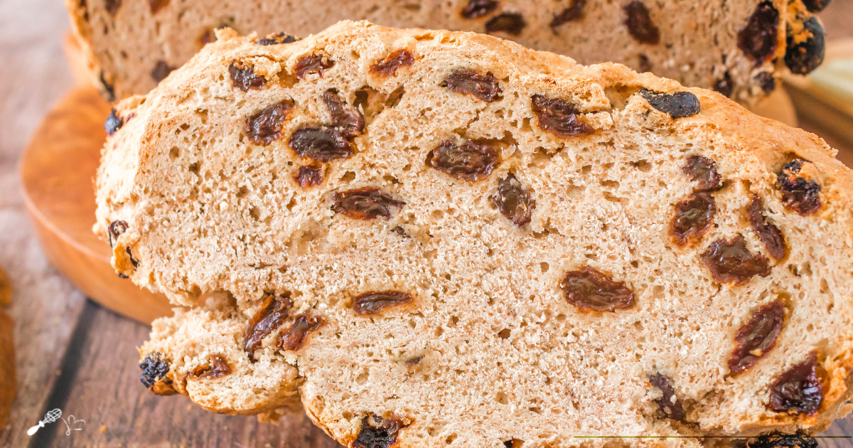 3/4 view of a slice of soda bread filled with raisins.