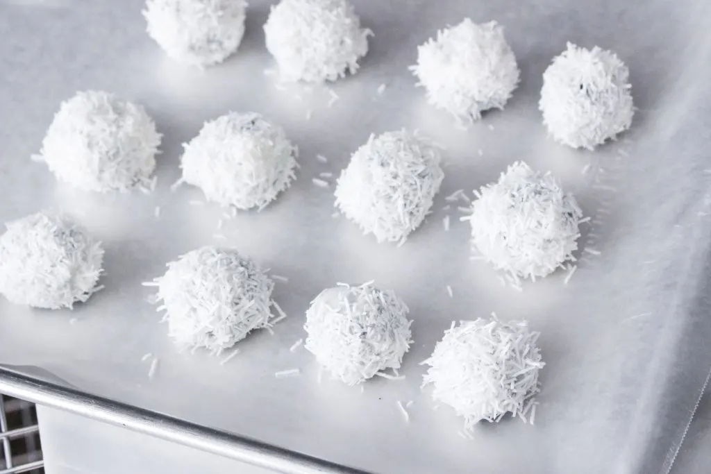 Coconut covered oreo balls sitting on a baking sheet.