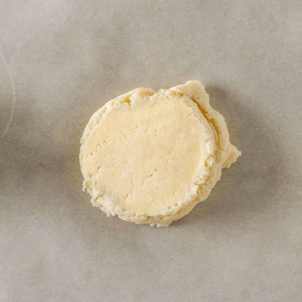 Top down view of a raw crumbl sugar cookie that's been flattened before baking. Hostess At Heart