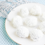 Oreo balls covered in coconut sitting on a white plate.