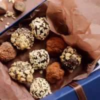 Top down view of a gift box filled with nut crusted and coco covered chocolate truffles.