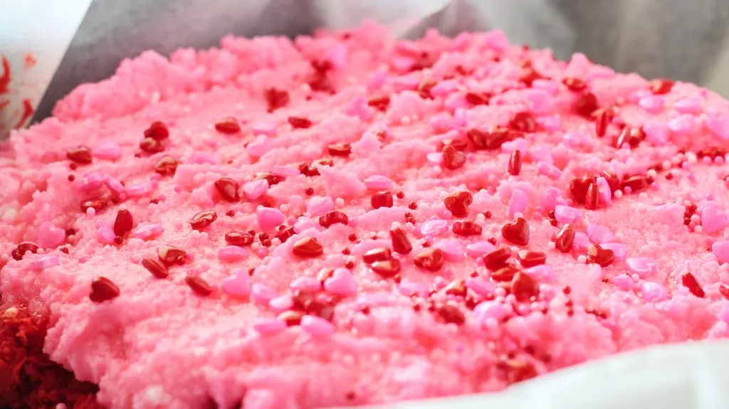 Valentine sprinkles over the top of pink and red layered fudge.