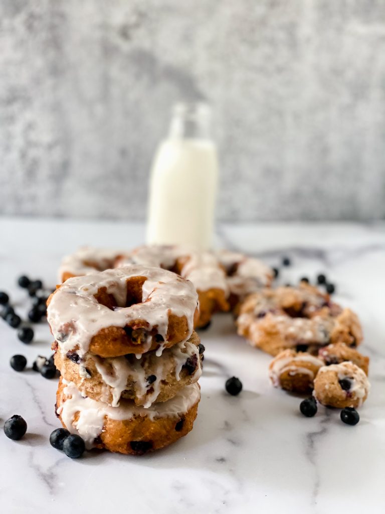blueberry donuts in front of a bottle of milk.